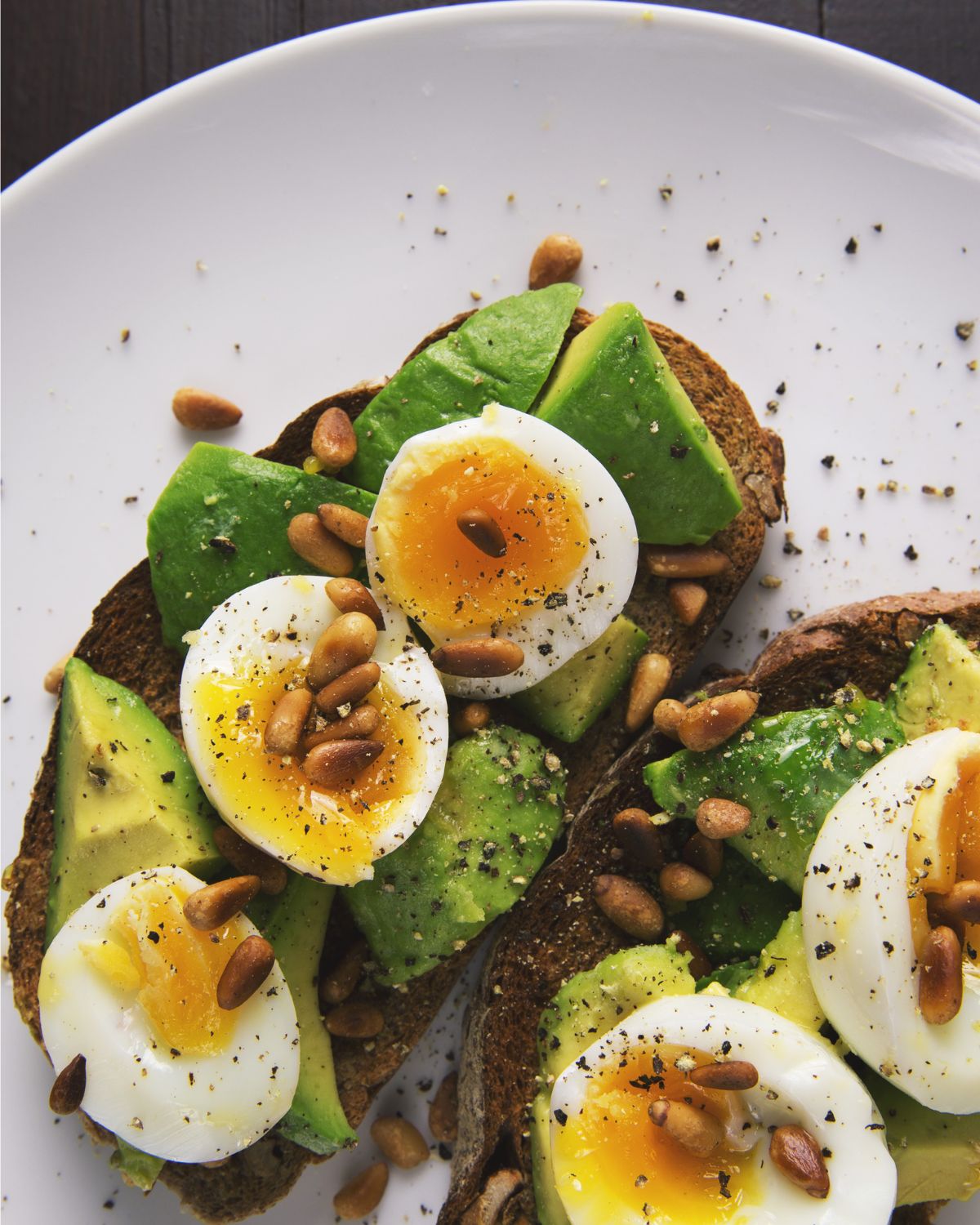 toast, avocado, egg and pine nuts on a plate to serve 