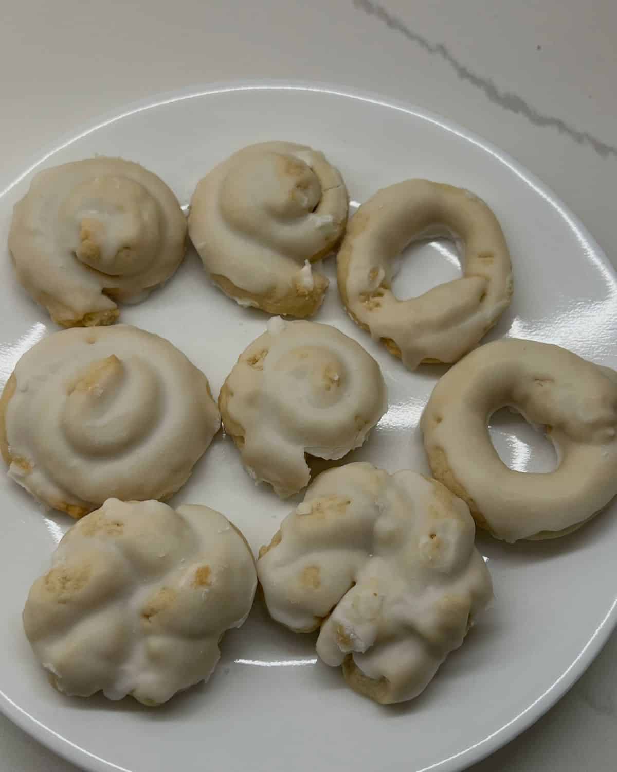 8 cookies laid out on a white plate n the counter 