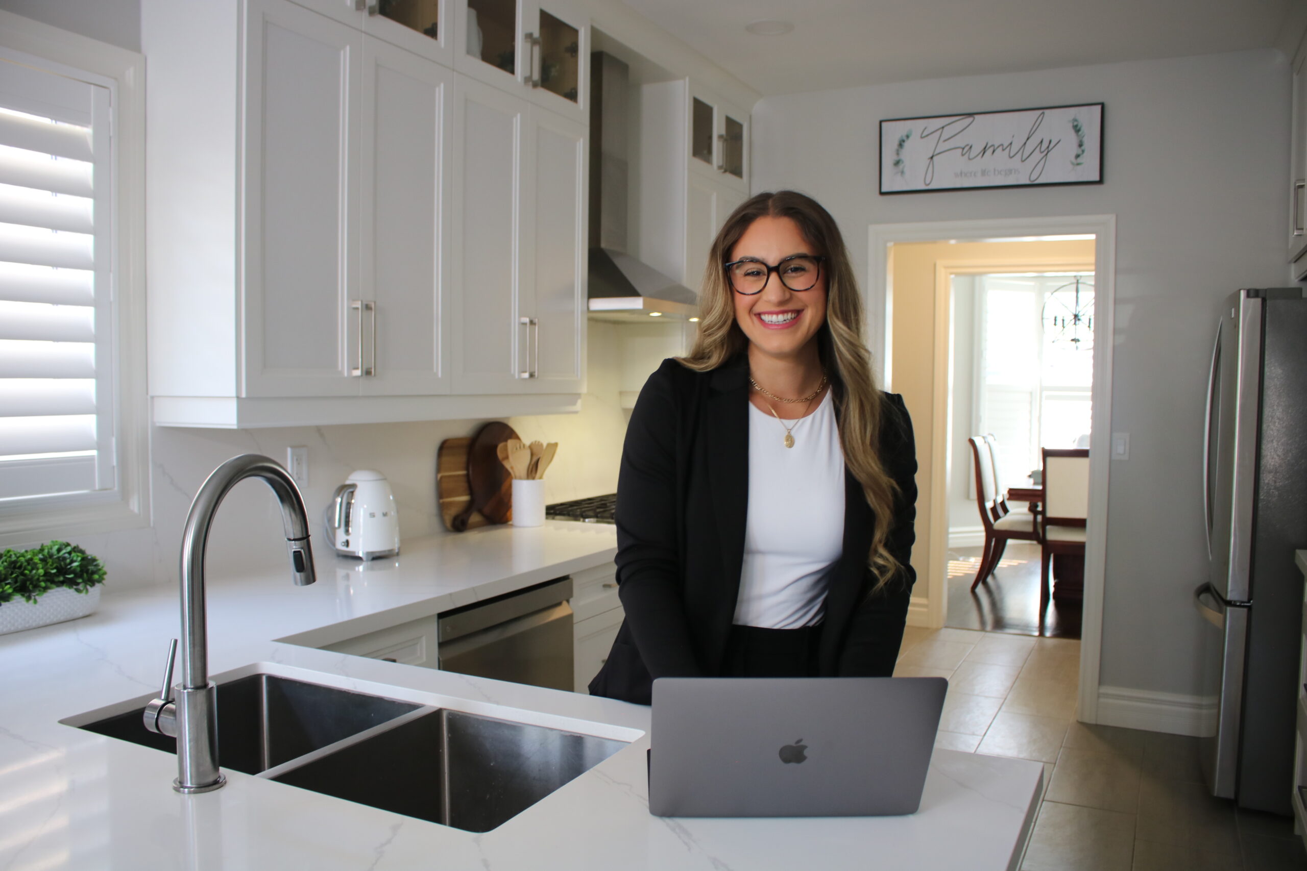 owner in kitchen with computer smiling at camera