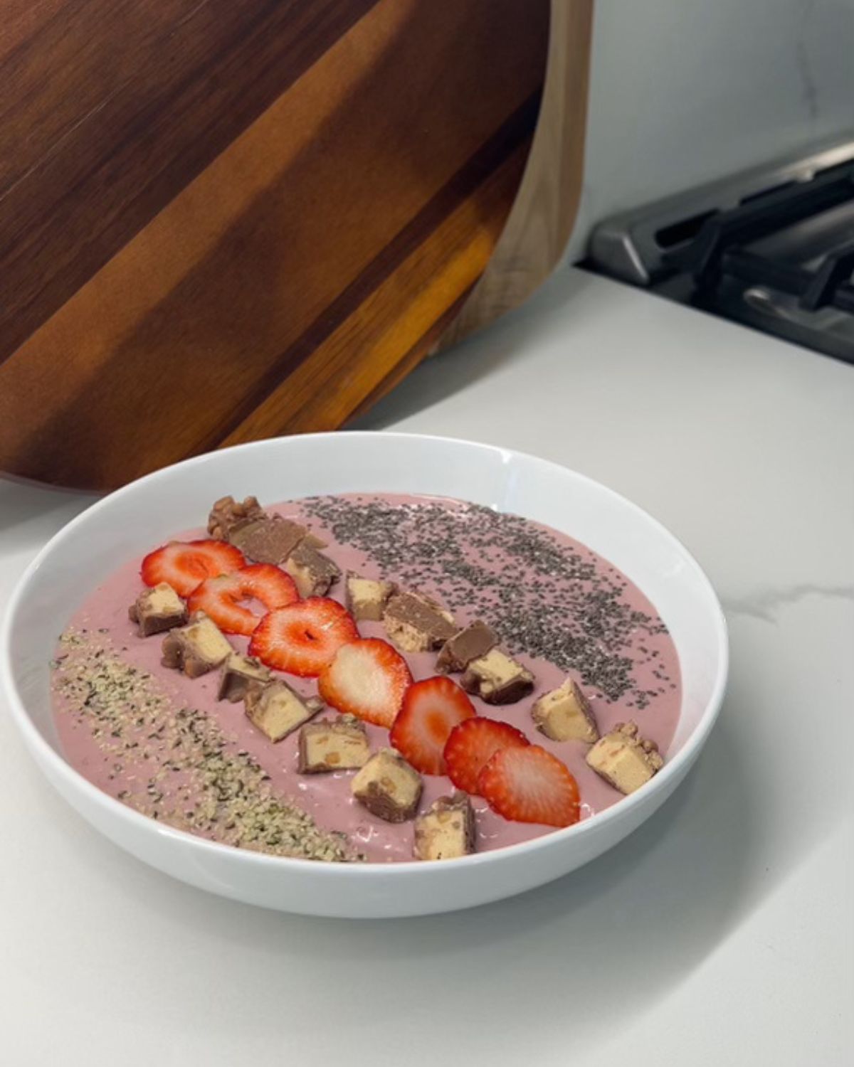 smoothie bowl topped with chia seeds, hemp hearts, strawberries and nuts