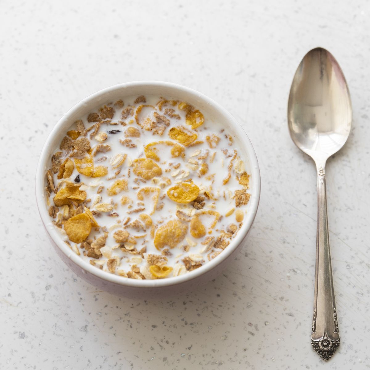 bowl of cereal on table with metal spoon beside