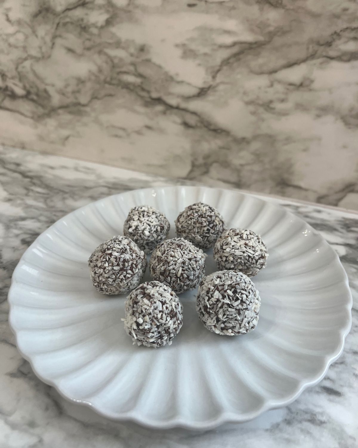 7 coconut date balls on white plate 