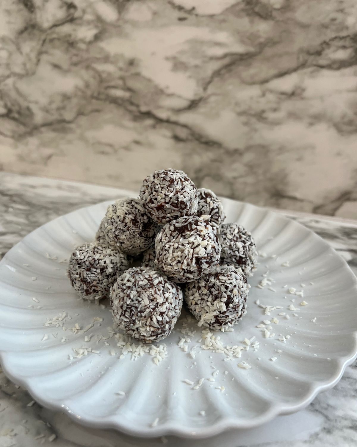 stack of coconut date balls - white plate 