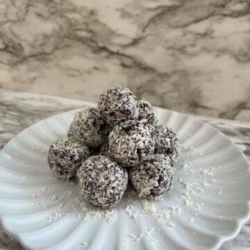 Coconut date balls stacked up on white plate