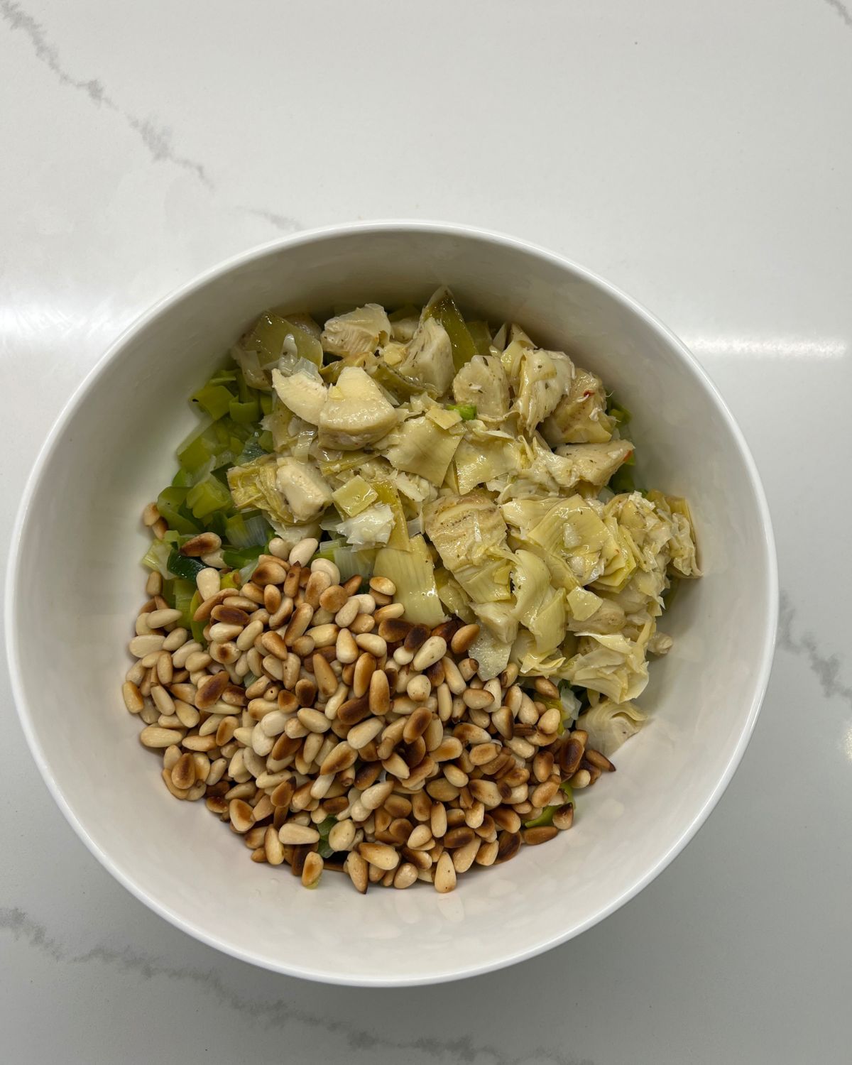 bowl with leeks and artichokes and pine nuts 