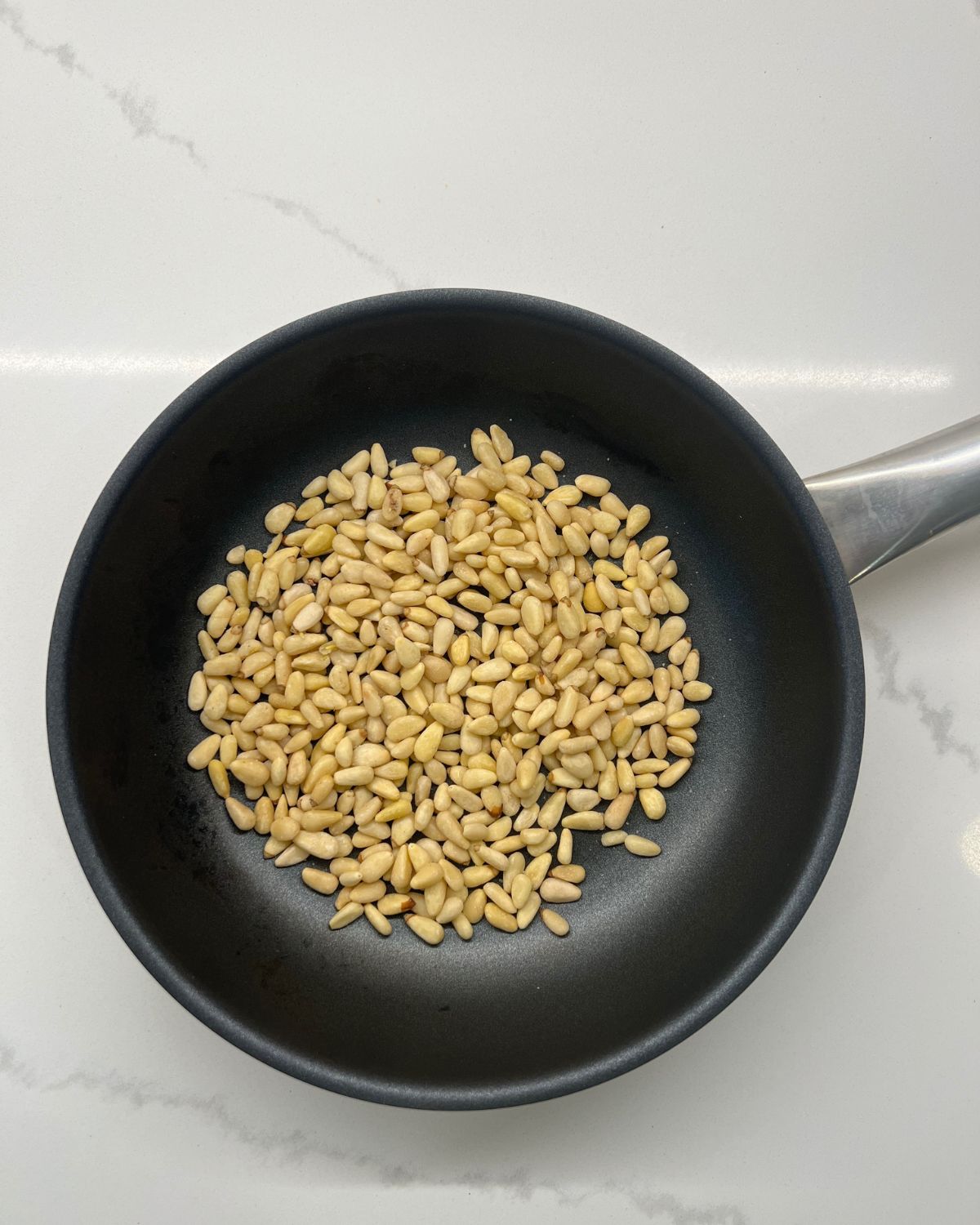 pine nuts on frying pan to be roasted 