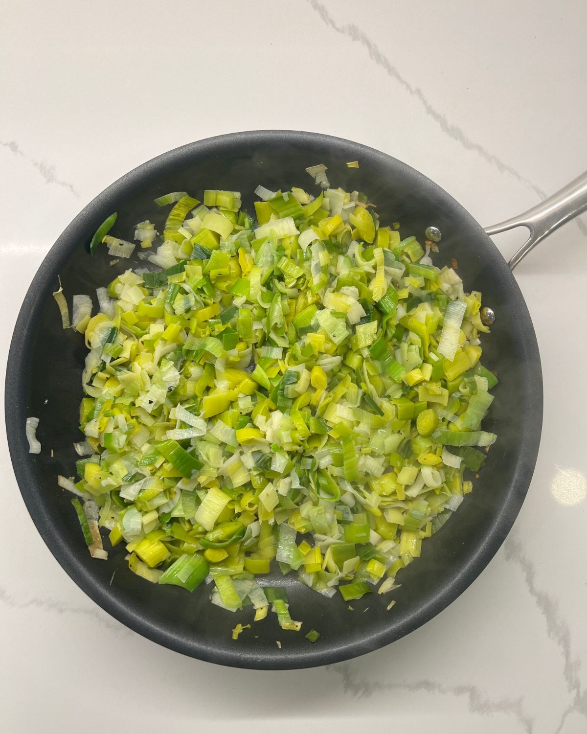 frying pan with leeks being sautéed. 