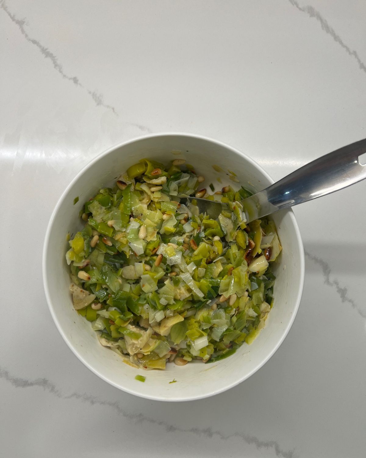 leek salad in serving bowl with metal spoon in it 