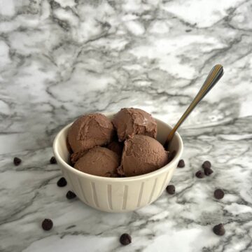 scoop of ice cream in bowl with spoon in it chocolate chips scattered around