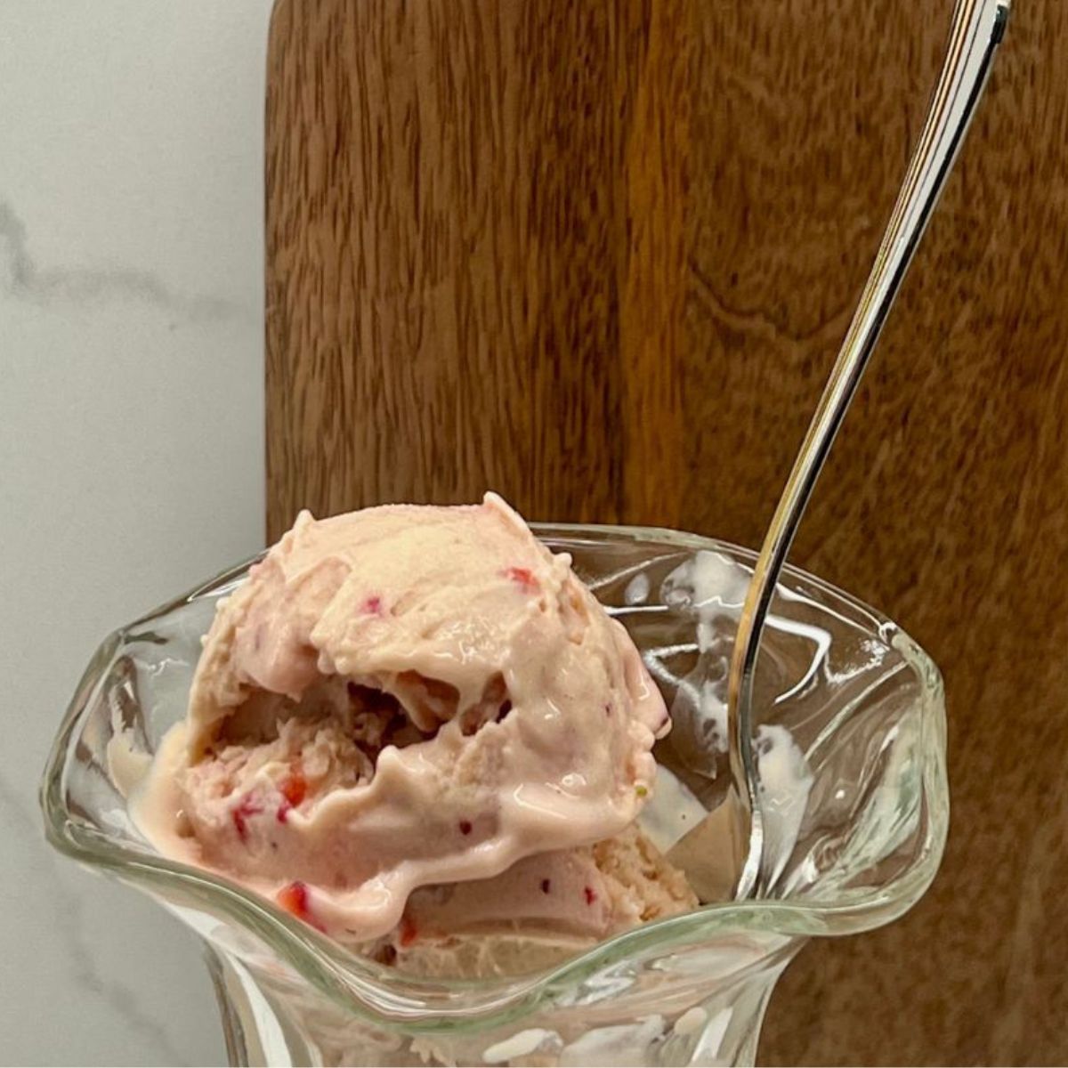 Ninja Creami Strawberry Ice Cream in a bowl behind a cutting board