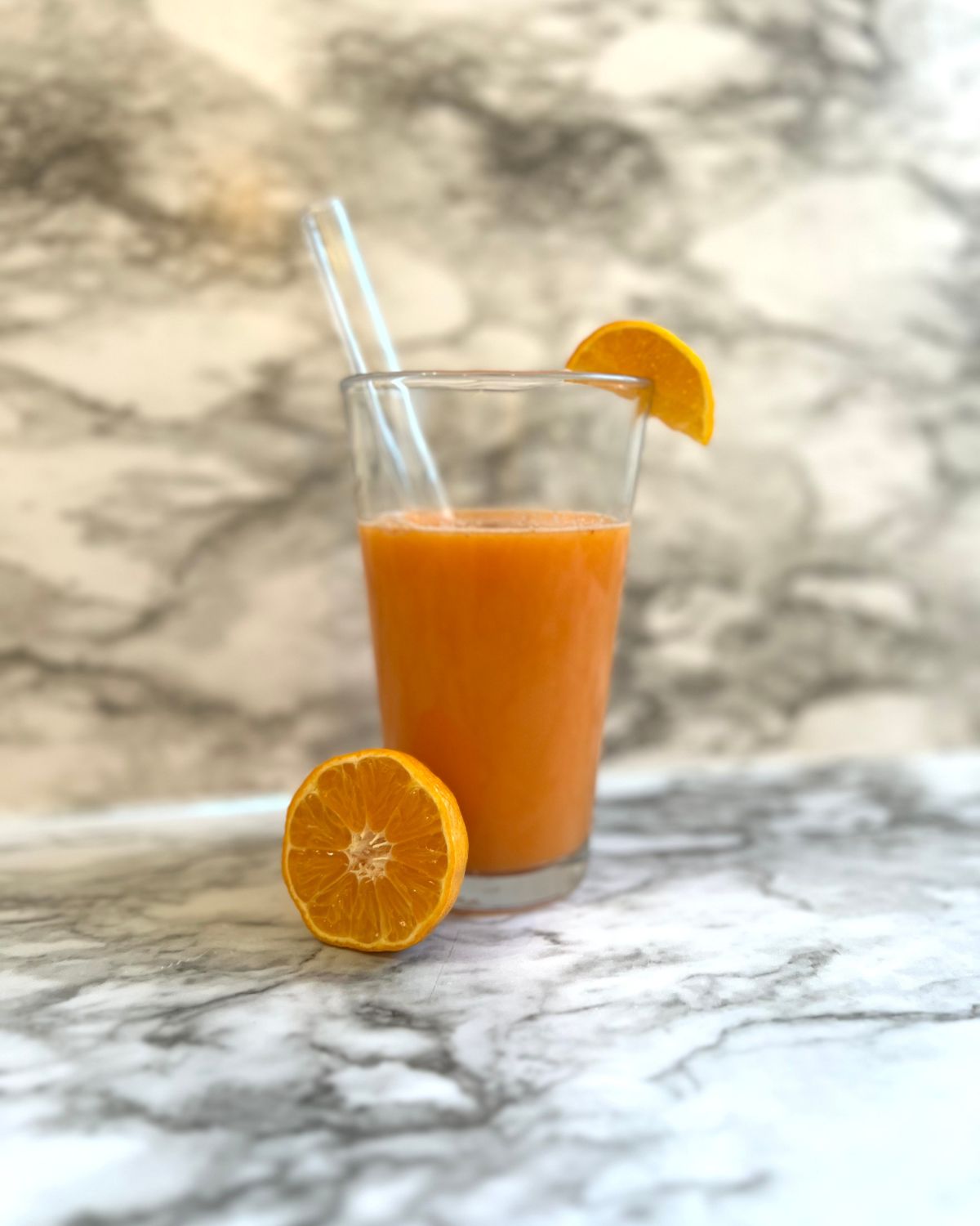 glass cup with juice instead with half an orange in front of the cup 