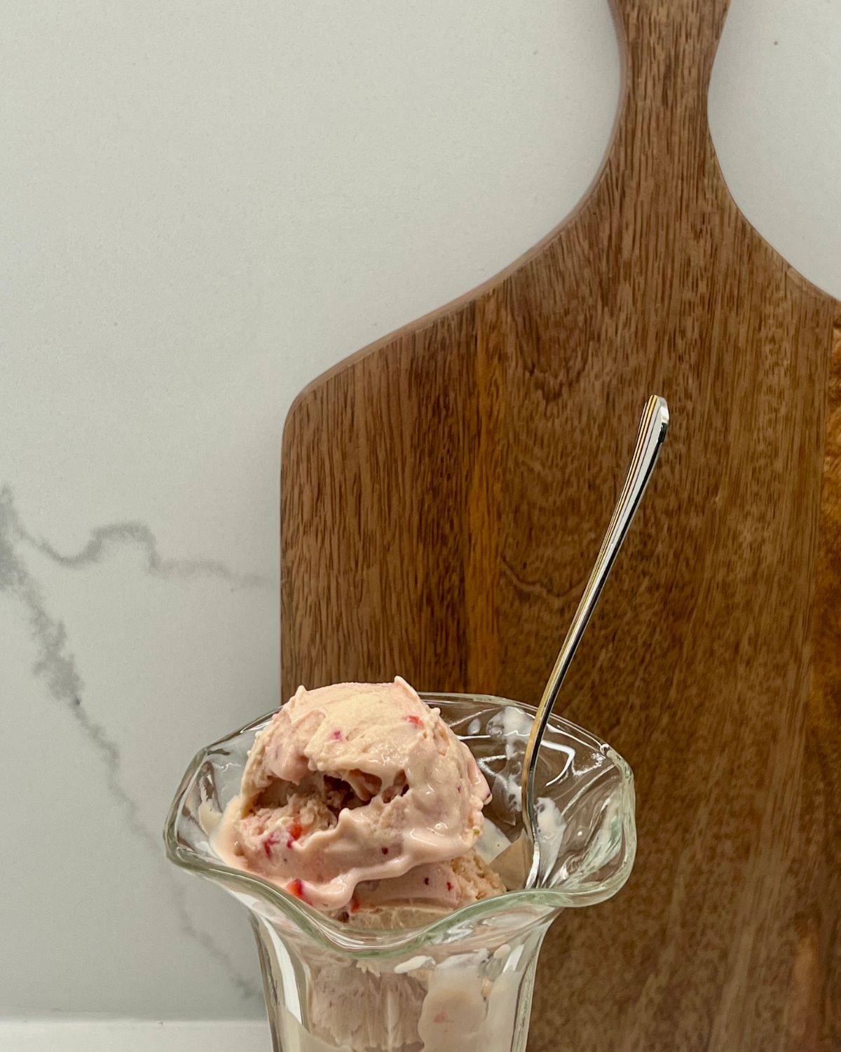 Ninja Creami Strawberry Ice Cream in a bowl behind a cutting board 