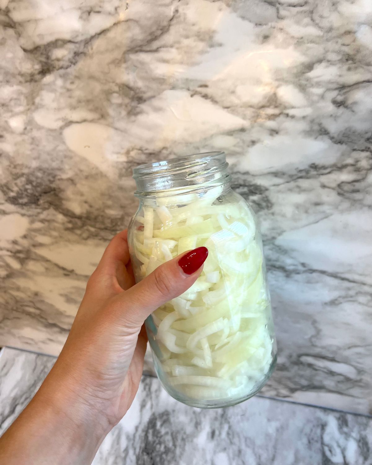 holding up mason jar filled with onions 