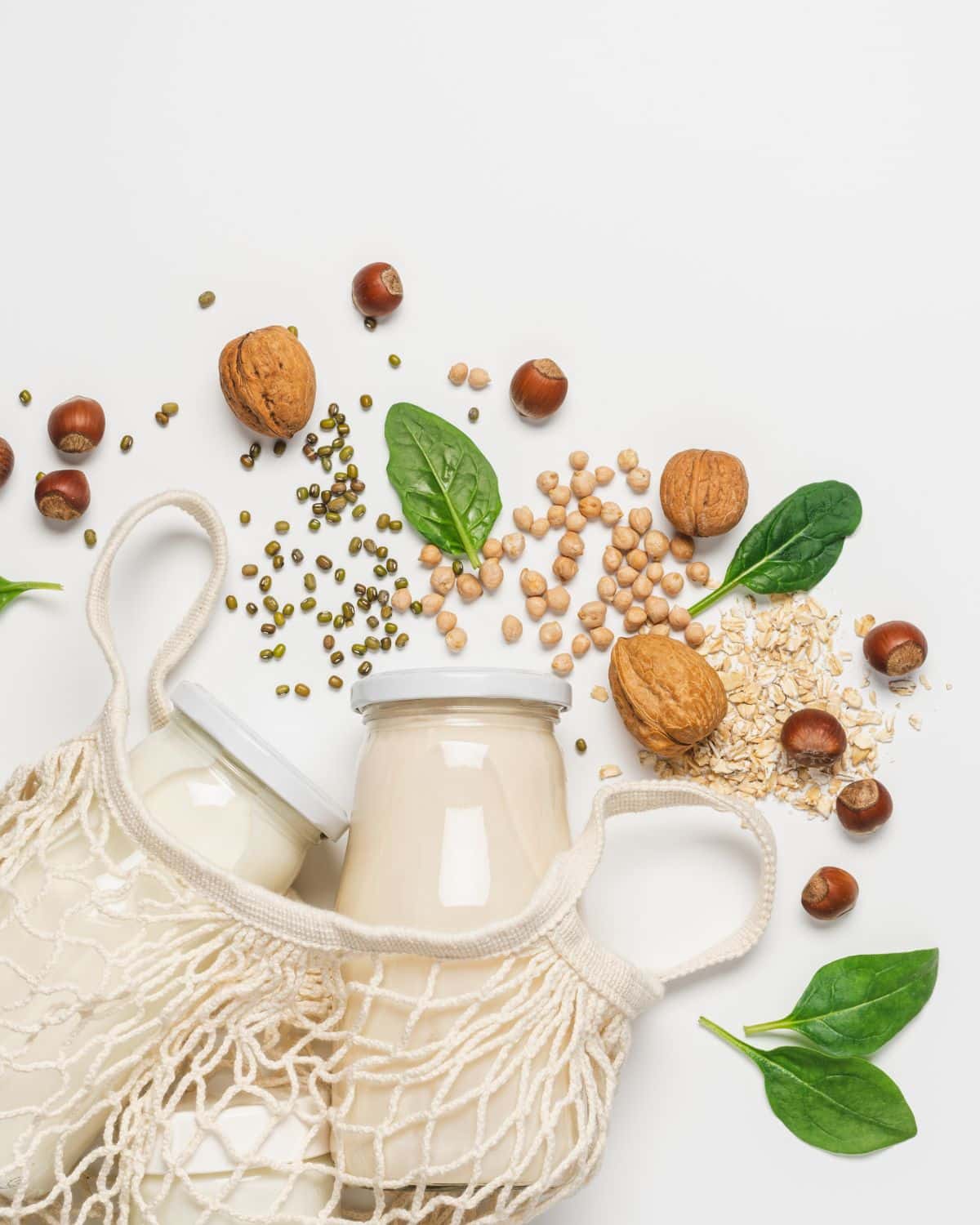 two containers of plant based milk with nuts and seeds scattered around the table