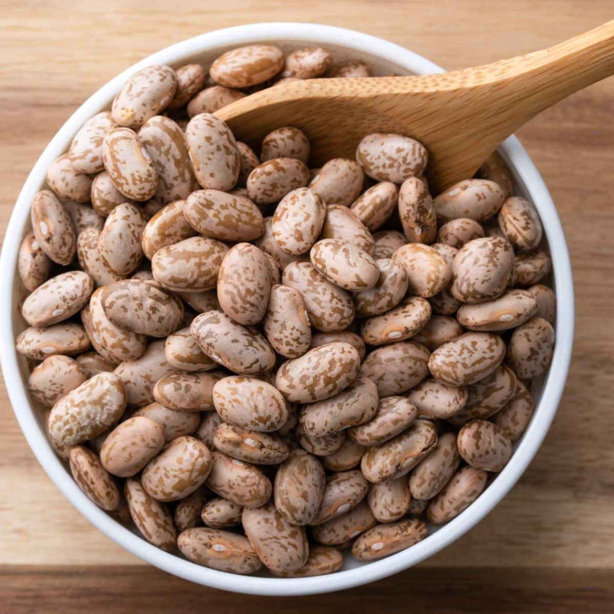 pinto beans in a bowl with a wooden spoon in the bowl