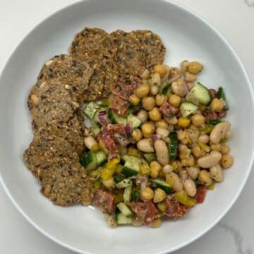 bean salad in white bowl with whole grain crackers