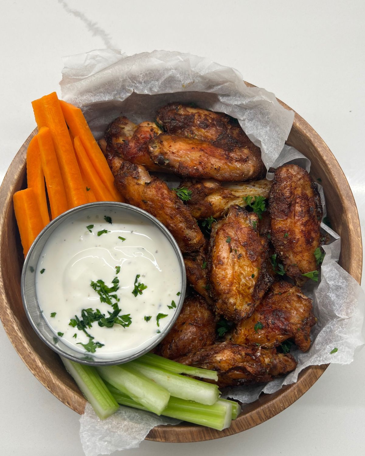 bowl of chicken wings with ranch dip on side and carrot and celery sticks 