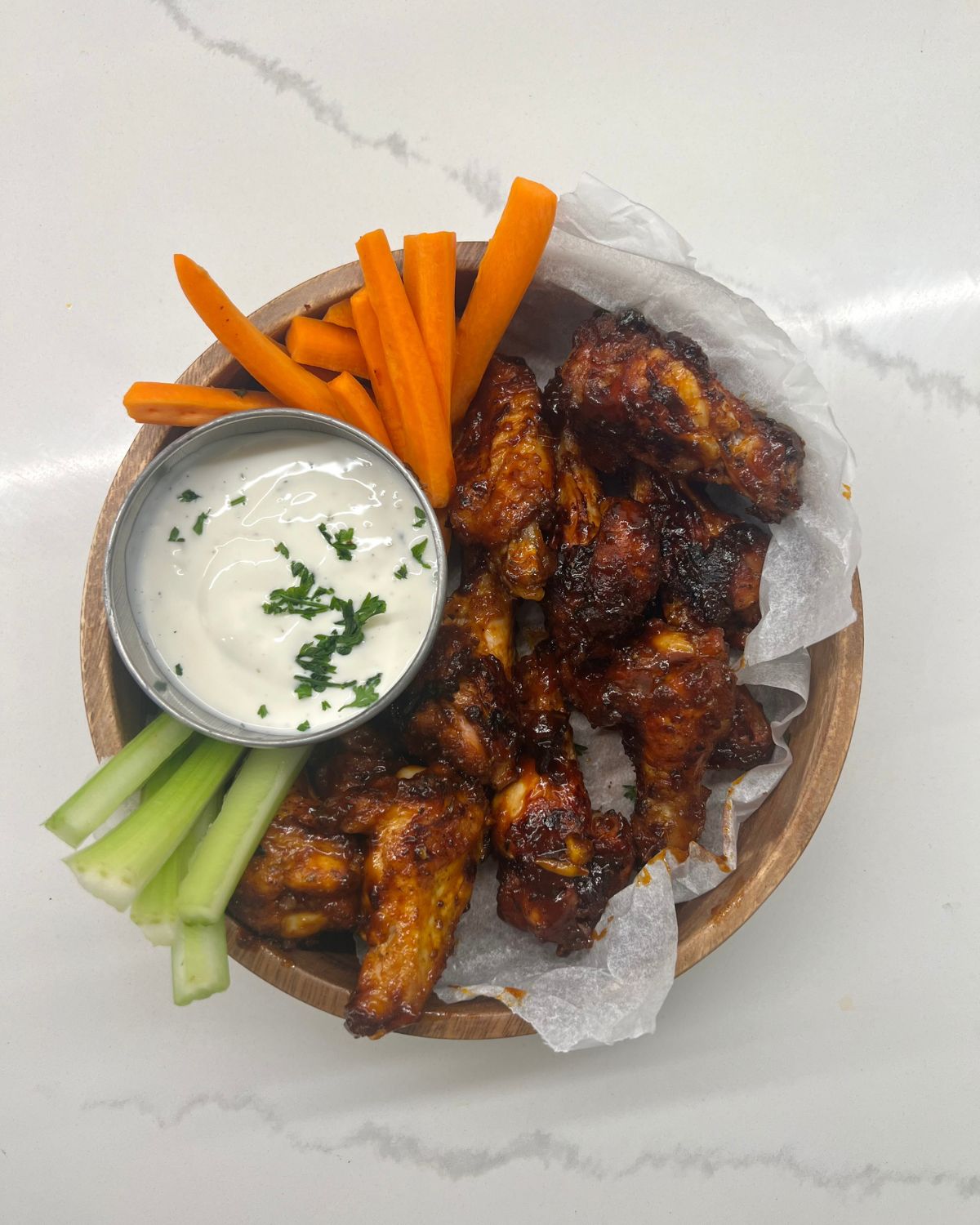 bowl of chicken wings with ranch dip on side and carrot and celery sticks 