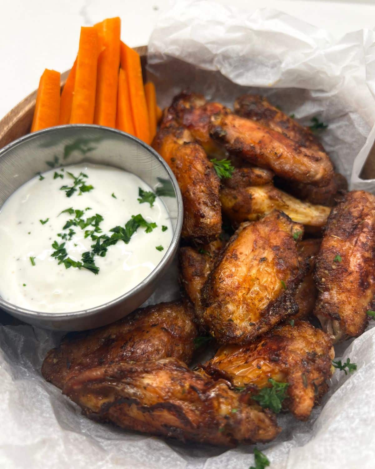 bowl of chicken wings with ranch dip on side and carrot and celery sticks 