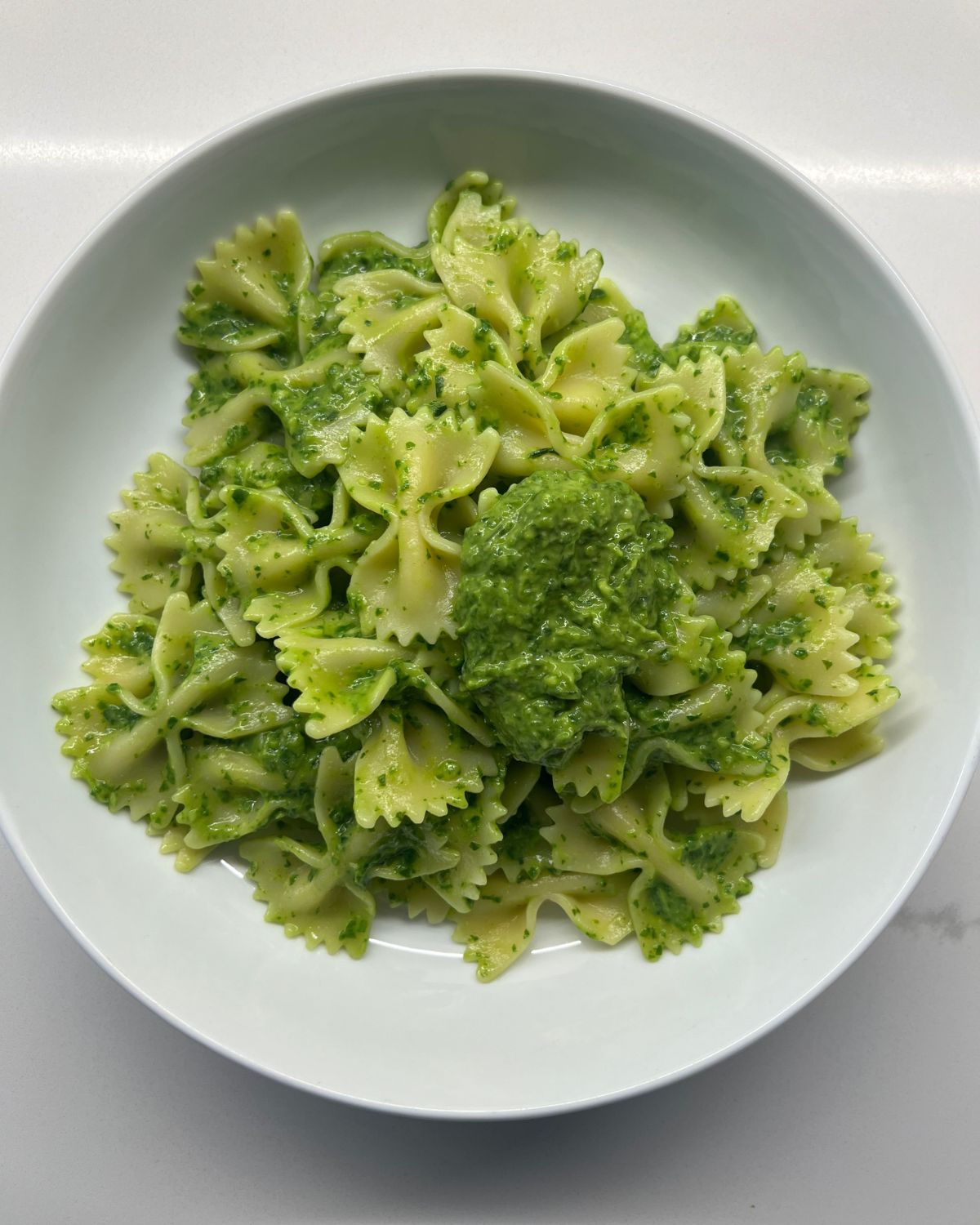 white bowl with the bow tie green sauce pasta 