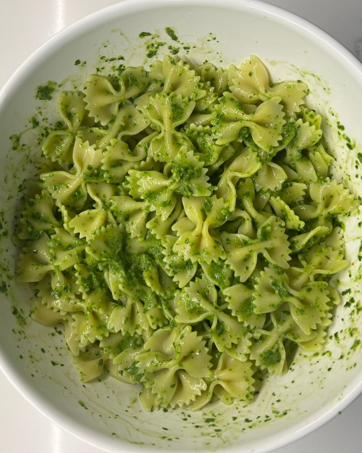 big bowl of all the pasta being mixed with the green sauce 