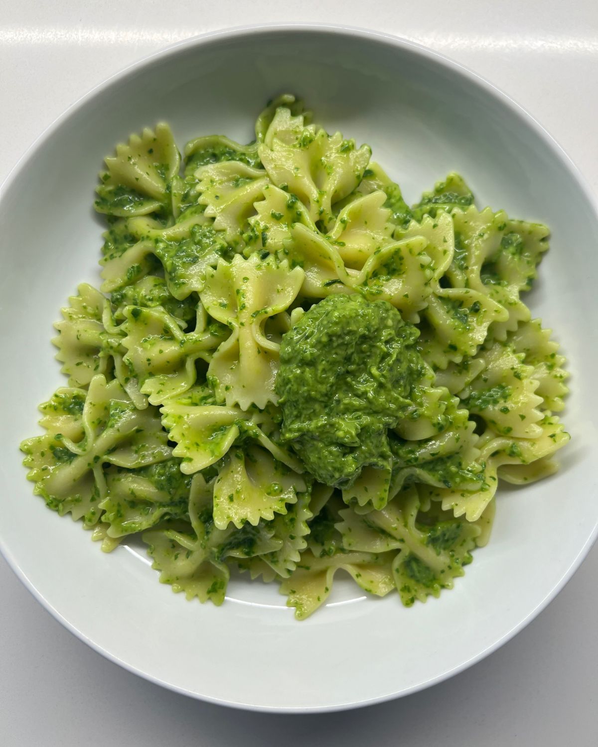 white bowl with the bow tie green sauce pasta