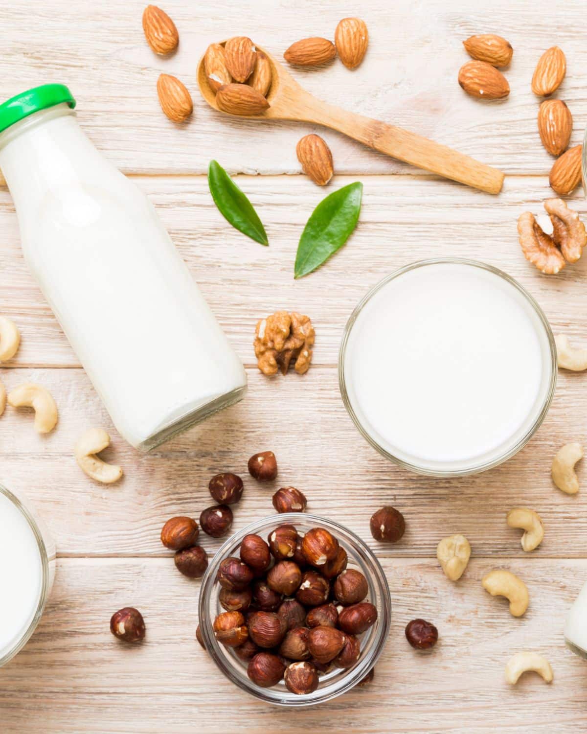 Plant based milk on a table with different nuts around table