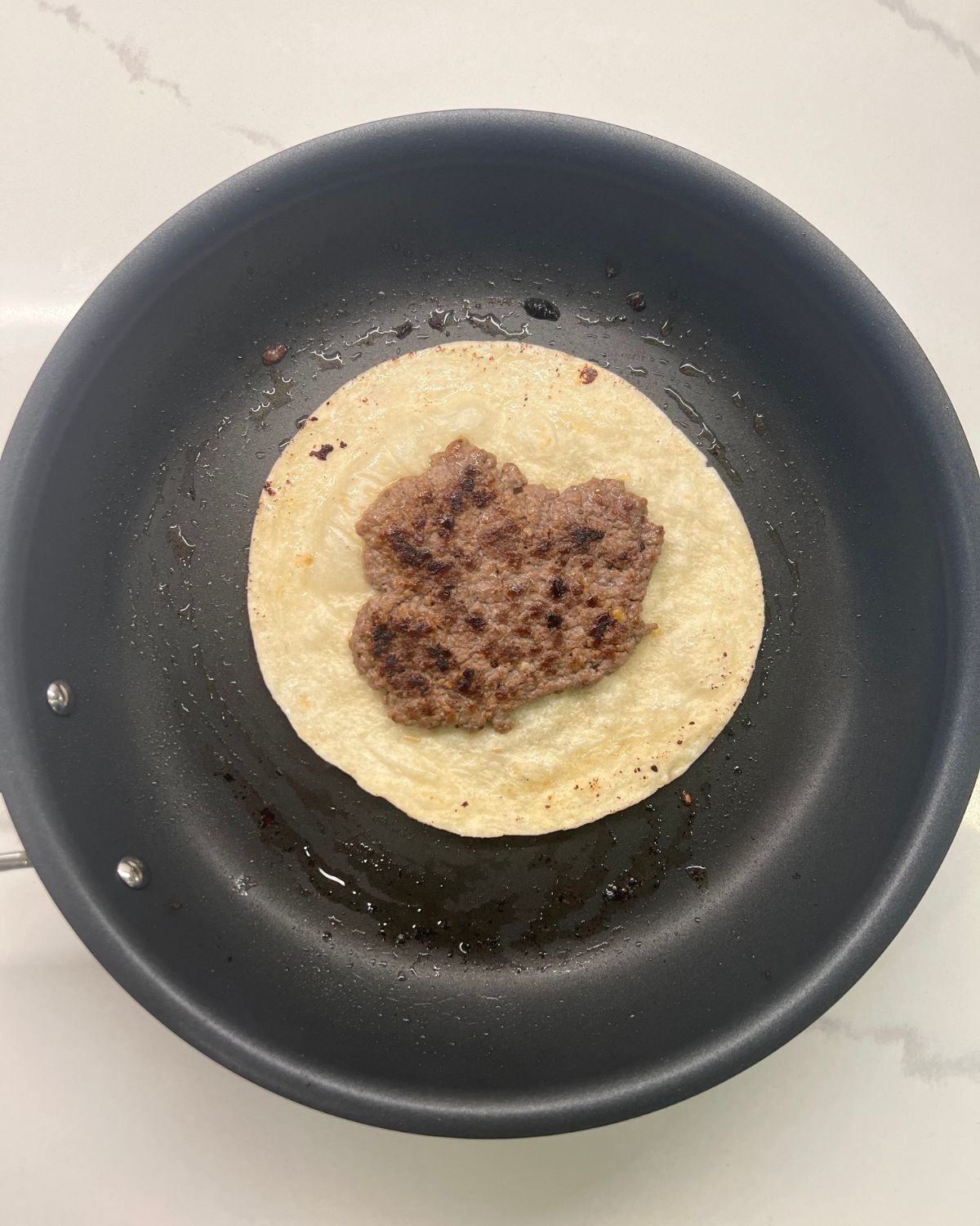 meat and tortilla on frying pan facing up 