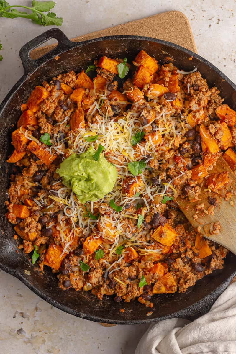 sweet potato taco skillet with gauc on top and spoon in 