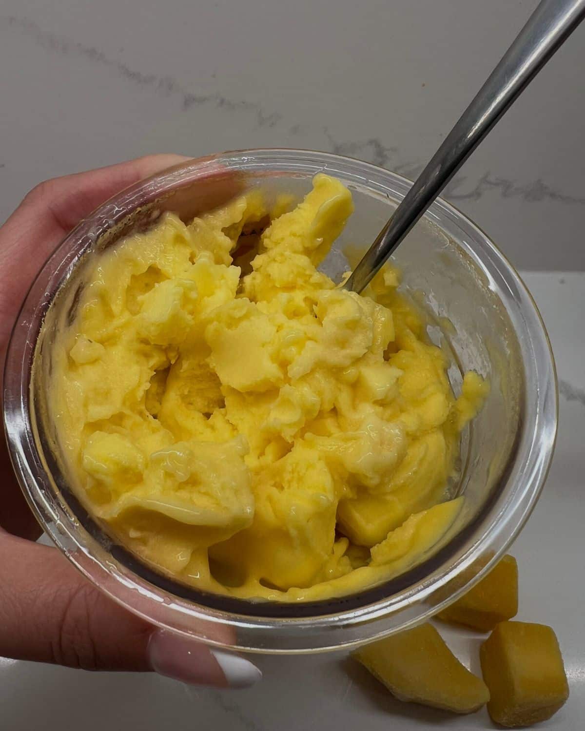 close up of the mango ninja creami in the pint with big spoon 