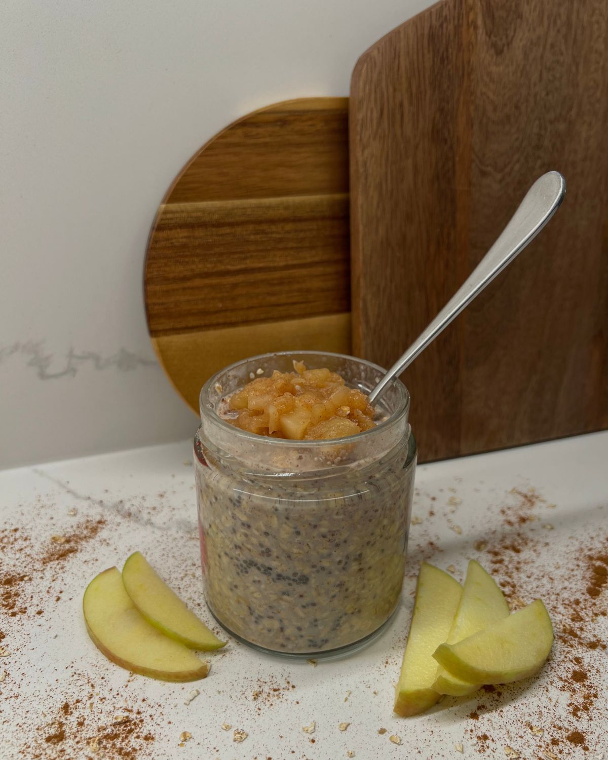 mason jar with apple cinnamon overnight oats with apple sauce on top and apple slices