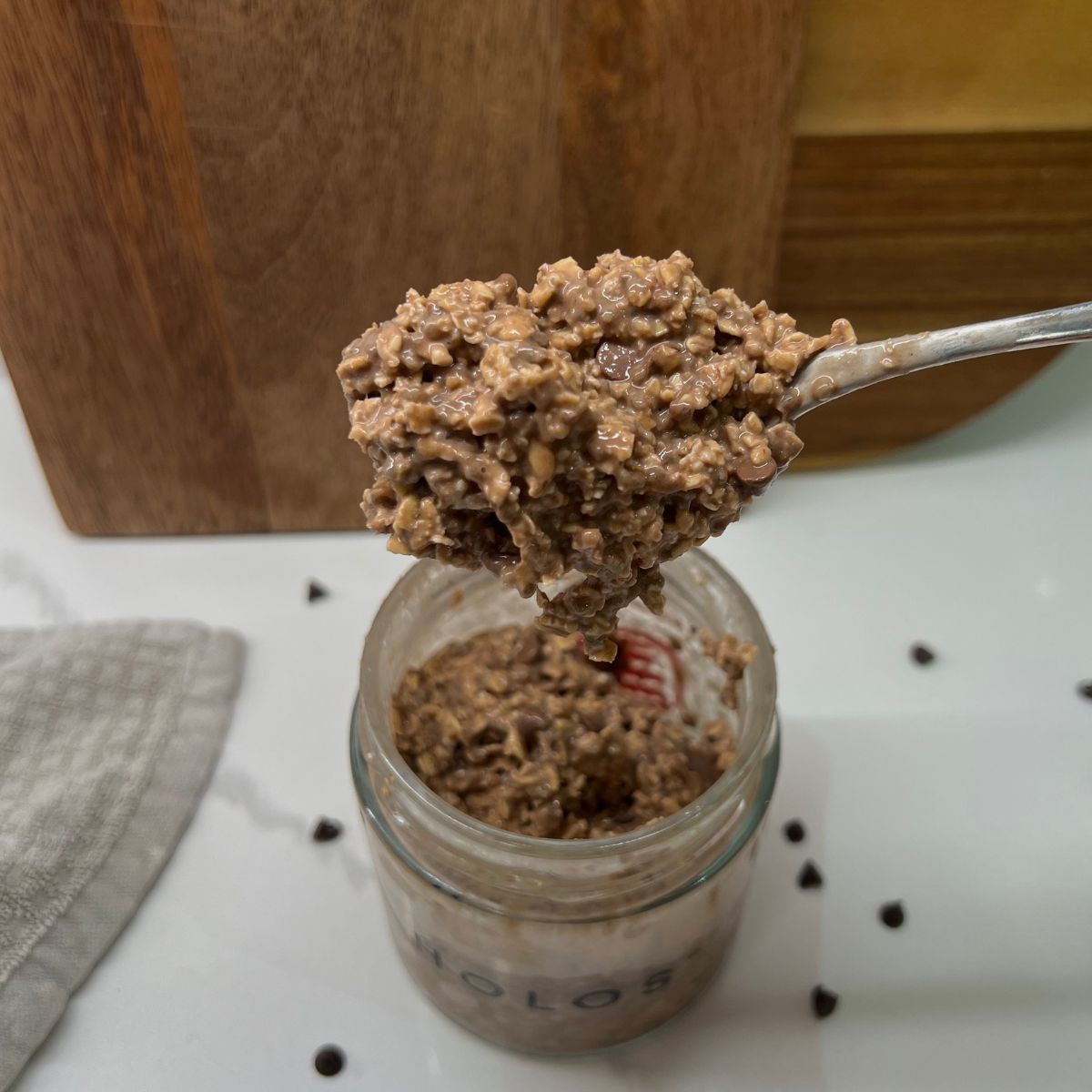 chocolate chip overnight oats in mason jar taking a big spoon of it to show camera