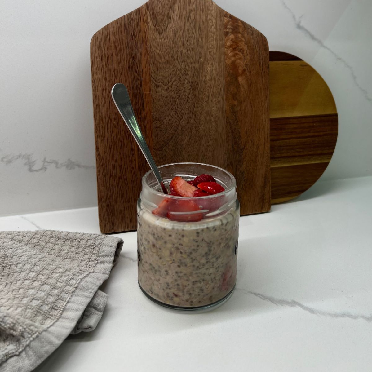strawberry oats in mason jar with spoon in it and strawberries on top