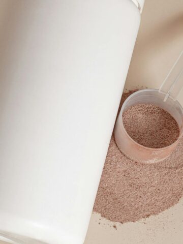 white container with a scoop of chocolate protein powder on the side