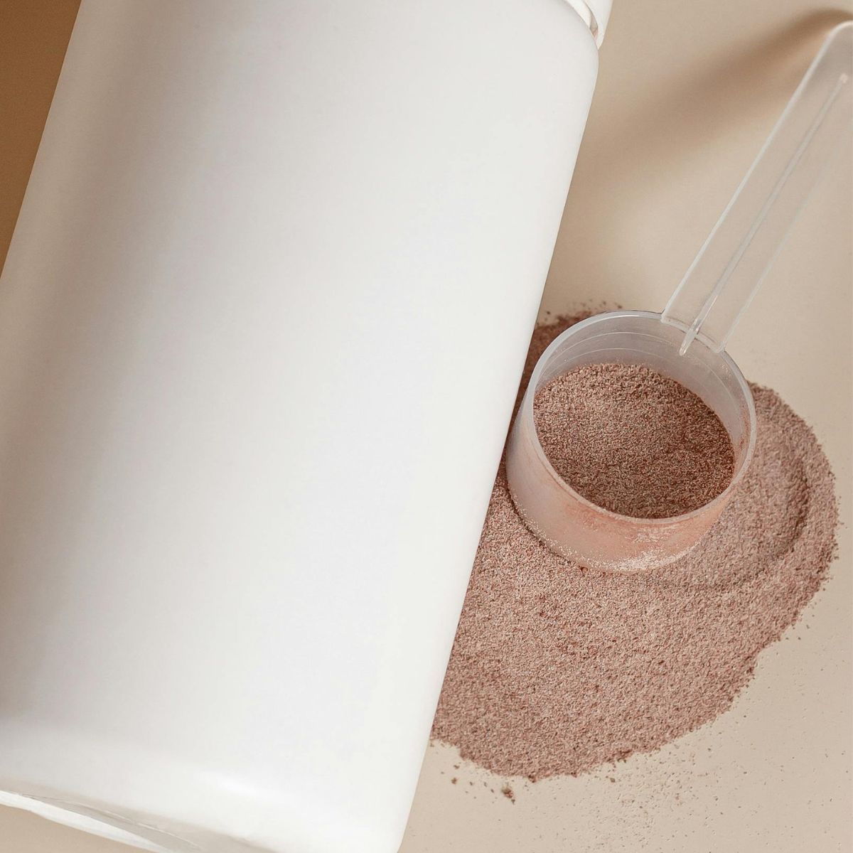 white container with a scoop of chocolate protein powder on the side